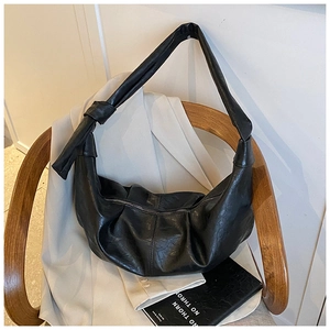 Close-up of black pleated faux leather hobo bag with unique knot shoulder strap detail