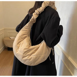 Fashionable beige quilted puffer bag with ruffled strap shown on a model's shoulder
