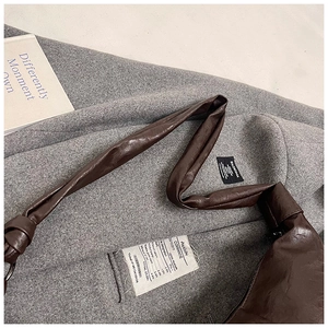 Detailed view of dark brown PU leather shoulder bag with knotted strap on a wool coat