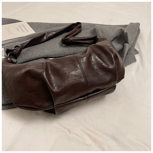Close-up of dark brown pleated leather texture on a slouchy hobo shoulder bag