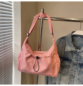 Detailed texture of pink corduroy shoulder bag with silver sparkles and drawstring pocket