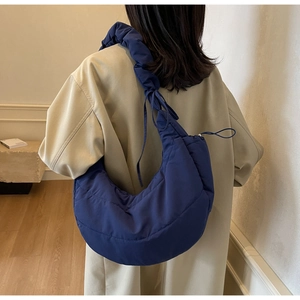 Detail of navy blue quilted dumpling bag featuring a unique ruched adjustable shoulder strap