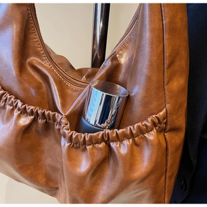 Detail der braunen Ledertasche mit elastischer Seitentasche und feiner Lederstruktur