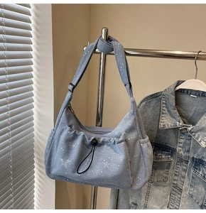 Detail of blue corduroy crossbody bag featuring silver star prints and drawstring pocket