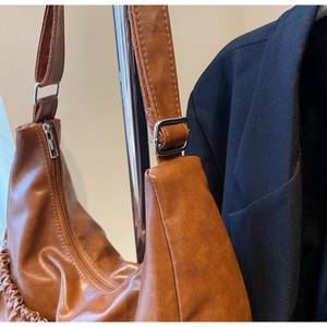 Detail der braunen Vintage-Schultertasche mit Silberschnalle und Falten-Design