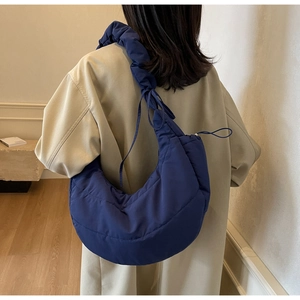 Detailed view of the dark blue quilted shoulder bag with ruffles on the strap and drawstring
