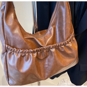 Detailansicht der braunen Kunstleder-Schultertasche mit modischer Faltentasche vorne