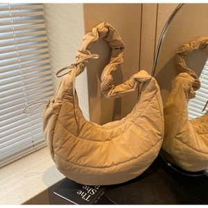 Detail of beige quilted crescent bag with ruffled strap and soft nylon texture