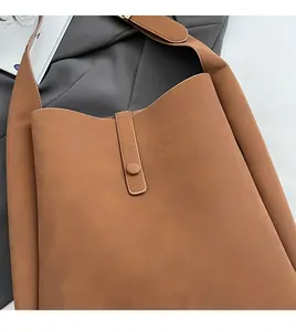 Detail shot of vintage brown leather tote bag showing soft suede texture and button closure