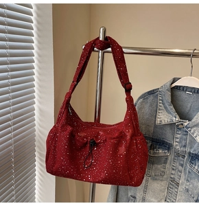 Close-up of red corduroy crossbody bag with adjustable wide strap and drawstring pocket