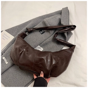 Detailed macro view of deep brown pleated leather hobo bag texture and wide strap knot