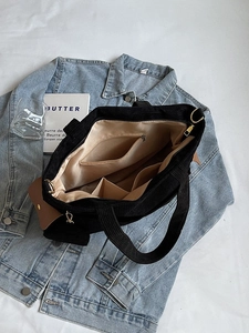 Black corduroy tote bag featuring multiple interior pockets and a spacious design