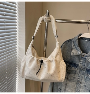 Detail of off-white corduroy hobo bag with subtle silver sequins and adjustable strap