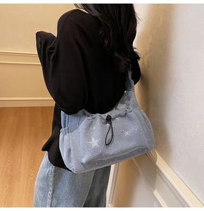 Detail of blue corduroy bag with star print and drawstring pocket shown on a model