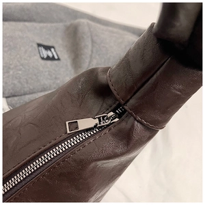 Close-up of dark brown leather texture with high-quality metal zipper on hobo bag