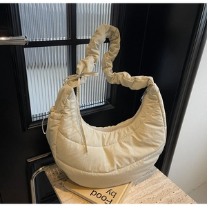 Detail of beige quilted crescent bag featuring a ruched strap and horizontal stitching