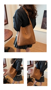 Detail view of brown matte leather tote bag featuring adjustable buckle and snap closure