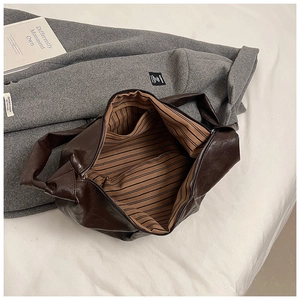 Detailed macro view of dark brown faux leather tote bag with striped lining and inner pocket