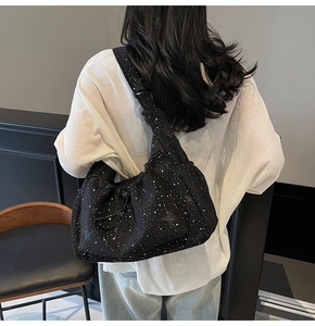 Detail of black corduroy crossbody bag with white polka dots and textured fabric finish