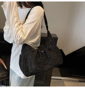 Detail of black nylon crossbody bag with star pattern texture and side drawstring feature