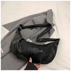 Detailed shot of a black PU leather hobo bag with a knotted strap and side label