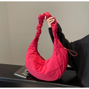Detail of fuchsia quilted crescent shoulder bag with pleated strap and nylon texture
