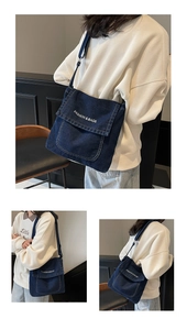Vista macro della borsa a tracolla in denim blu con testo bianco FASHION & BAGS e patta