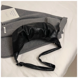 Detail of black pleated croissant bag texture on grey suit background