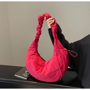 Close-up of rose red quilted puffer bag showing ruched handle and zipper detail