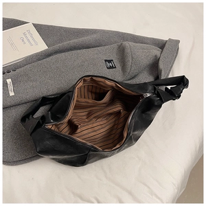Detail view of large leather dumpling bag featuring striped lining and interior zip pocket