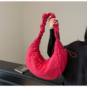 Detail of red quilted crescent bag with ruffled strap and puffer texture for women