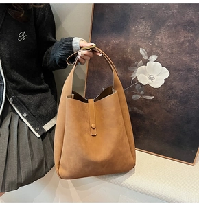 Detailed macro view of brown faux suede shoulder bag with vertical strap closure