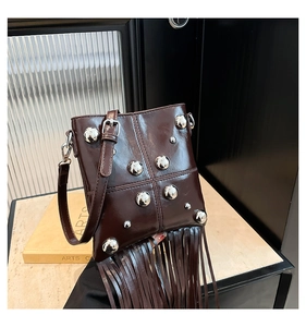 Detalle de bolso bandolera de cuero marrón oscuro con remaches plateados y flecos largos