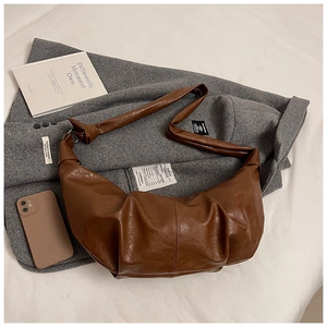Macro detail of brown pleated leather texture and vertical stitching on the crescent bag