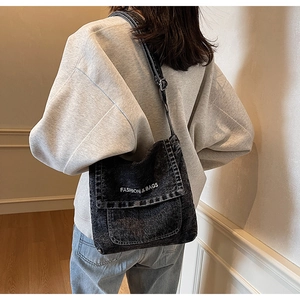 Dettaglio della borsa a tracolla in denim nero con scritte bianche e cinghia regolabile