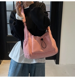 Detail of light pink corduroy crossbody bag with drawstring pocket and sequin accents