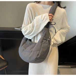Detail of dark grey quilted down crossbody bag with adjustable drawstring bow shoulder strap