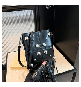 Detalle de un bolso negro vintage con flecos, remaches plateados y borlas largas