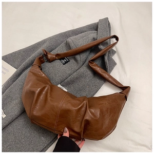 Detail of soft brown pleated leather texture and knot design on crescent shoulder bag