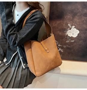 Detail of a brown leather tote bag with a matte finish and adjustable slim shoulder strap