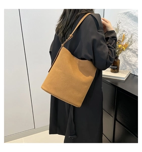 Detail view of large brown faux suede bucket bag with adjustable strap on model