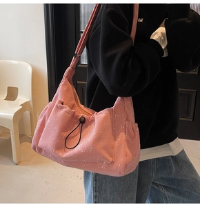 Pink corduroy crossbody bag with drawstring pocket and white ink splatters on model
