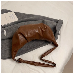 Detailed close-up of dark brown pleated croissant bag with textured leather and metal zipper