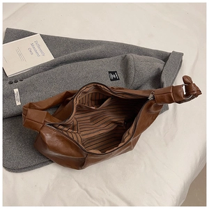 Detail view of large brown hobo bag with striped lining and secure metal zipper