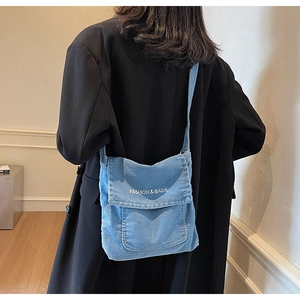 Dettaglio della borsa a tracolla in denim blu con ricamo Fashion & Bags sulla patta