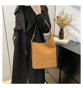 Brown suede hobo shoulder bag with adjustable strap worn with a black coat