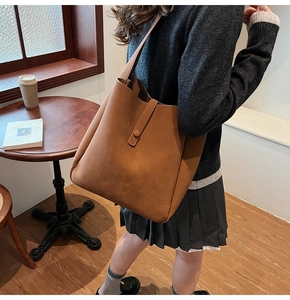 Detail shot of vintage caramel brown leather tote bag with wide strap and matte texture