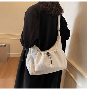 Close-up of white corduroy shoulder bag featuring silver sequins and drawstring pocket detail