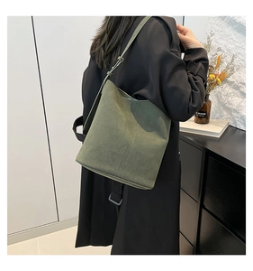 Detail of dark green bucket bag with matte suede texture and adjustable shoulder strap
