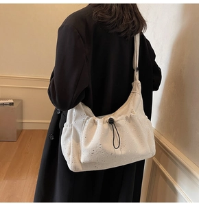 Detail of beige corduroy crossbody bag with drawstring pocket and adjustable strap